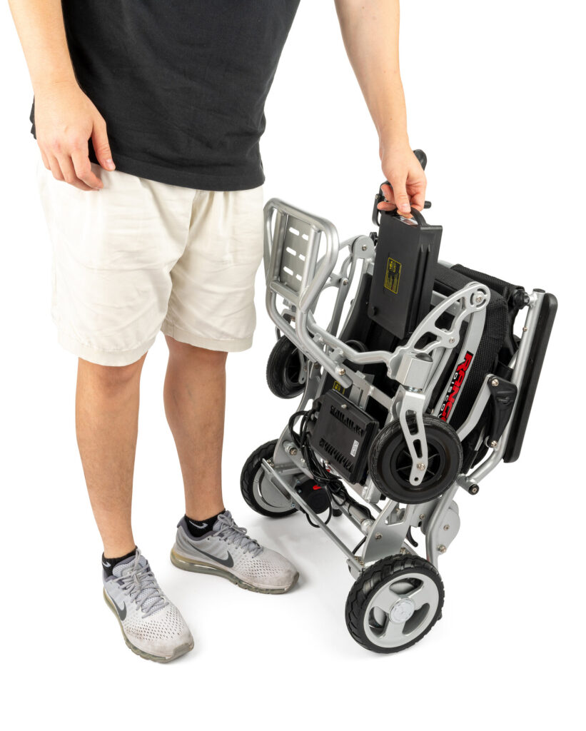 Porto Mobility Ranger Super Lightweight folding power wheelchair folded and held upright by a standing man