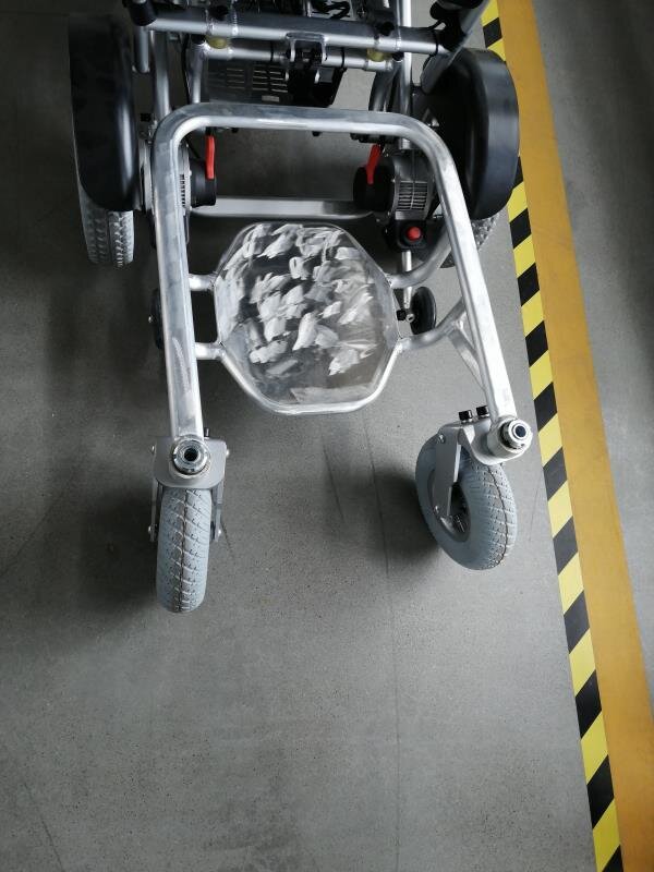 Porto Mobility Ranger The Beast folding power wheelchair, front frame and casters from above on a concrete floor